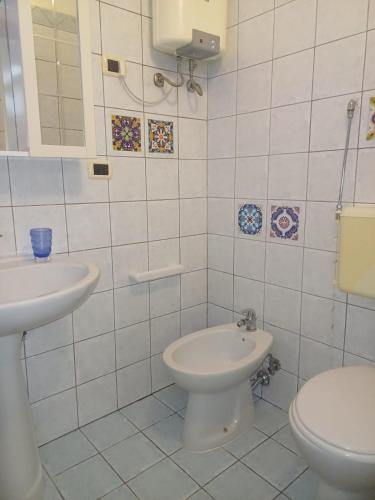 a white bathroom with a toilet and a sink at Flore's House Ostuni in Villanova di Ostuni