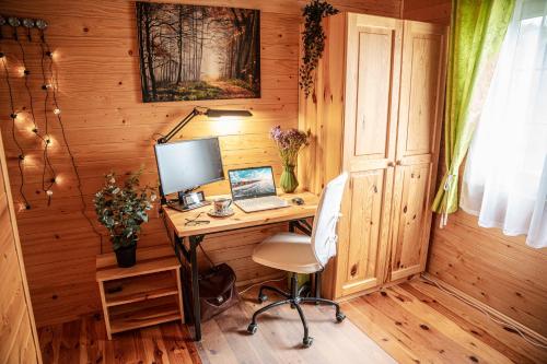 a desk with a computer in a wooden room at Dom Marzeń z jacuzzi pod gwiazdami in Kopalino