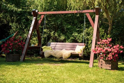 a sheep sitting on a swing in a yard at Dom Marzeń z jacuzzi pod gwiazdami in Kopalino
