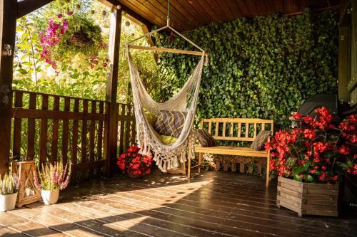 a hammock on a patio with flowers and plants at Dom Marzeń z jacuzzi pod gwiazdami in Kopalino