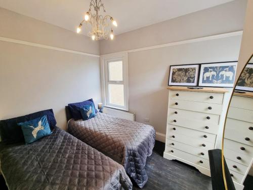 a bedroom with two beds and a dresser at Bridgerton House - Detached 5-bedroom Property in Gravesend