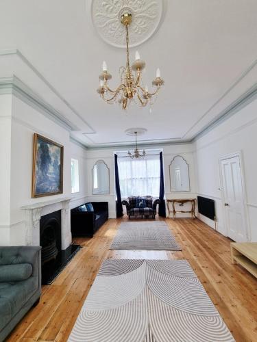 a living room with a chandelier and a fireplace at Bridgerton House - Detached 5-bedroom Property in Gravesend