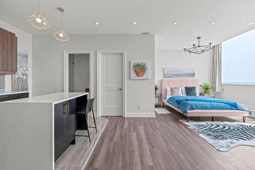a white bedroom with a bed and a kitchen at Bright Suites Finch West steps to Metro in Toronto