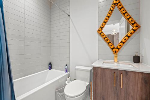 a bathroom with a tub and a toilet and a mirror at Bright Suites Finch West steps to Metro in Toronto