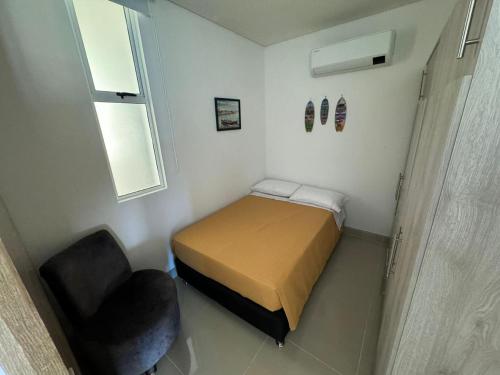 a small bedroom with a bed and a chair at Reserva Del Mar Apartamentos in Gaira