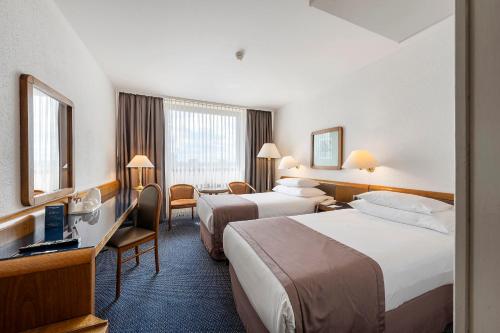 a hotel room with two beds and a desk at Panorama by Verdi Hotels in Prague