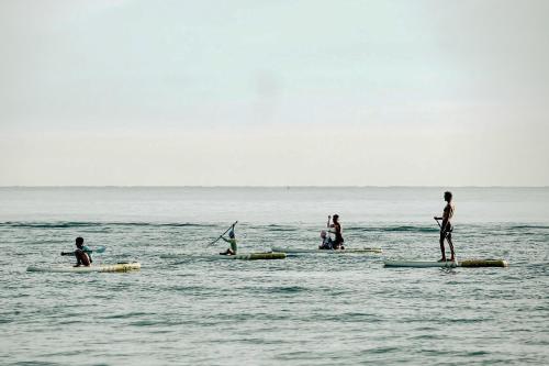 a group of people on surfboards in the ocean at Hoian Tranquil Beach Villa in An Bang