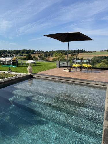 a swimming pool with an umbrella and a table and chairs at Le Domaine de la Vallée in Vernon