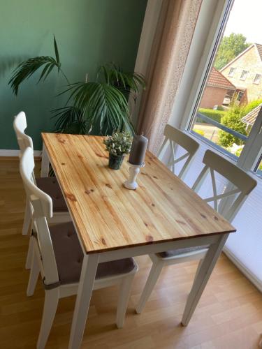 a wooden table and chairs in a room with a window at ZWITSCHERNEST Stilvolle helle Ferienwohnung Gästezimmer Monteurwohnung für 1 bis 6 Personen 3 Zimmer 60 qm in Itzehoe