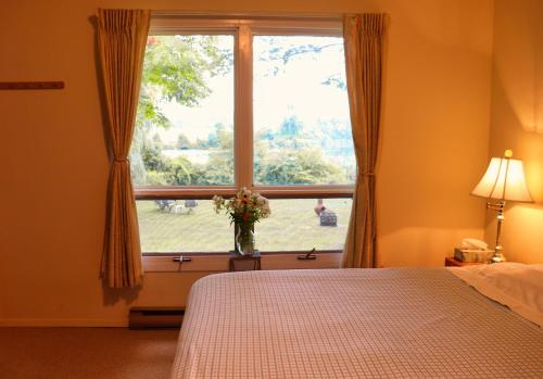 - une chambre dotée d'une fenêtre avec un vase de fleurs dans l'établissement Cottage on the Pond, à Millbrook