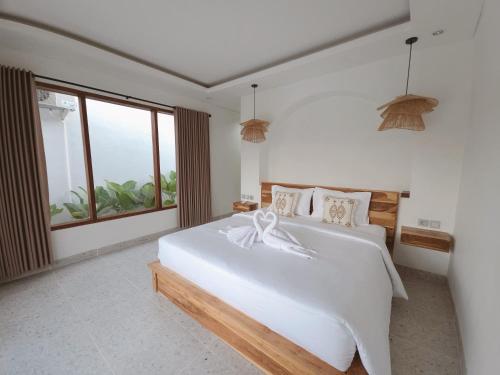 a bedroom with a large white bed with a large window at The Mahatama Uluwatu in Uluwatu