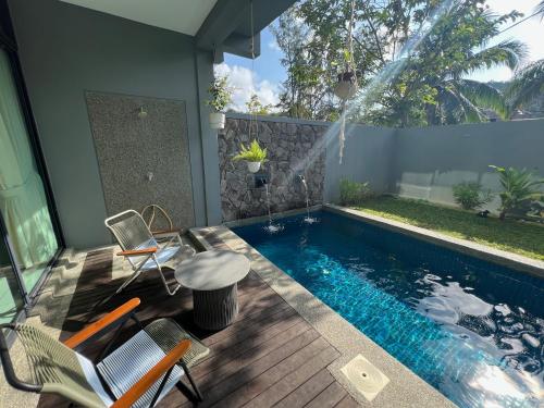 a swimming pool in a backyard with chairs and a table at Malibu 2BR Villa - Private Pool Langkawi in Pulau Tepur