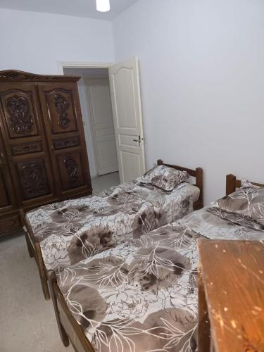a bedroom with two beds and a wooden dresser at Appartement de plage f in As Suwaysah
