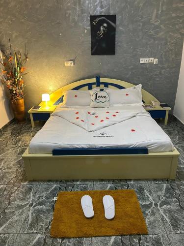a bed with a pair of white slippers on it at Prodiges Hôtel in Yaoundé