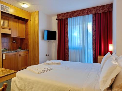 a hotel room with a white bed and a window at Residence Les Coupoles in Champoluc