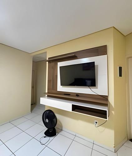 a living room with a television on a wall at Casa com piscina 03 quartos até 10 pessoas in Rio Branco