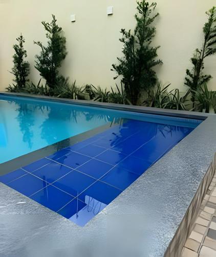 a blue swimming pool with trees in the background at Casa com piscina 03 quartos até 10 pessoas in Rio Branco