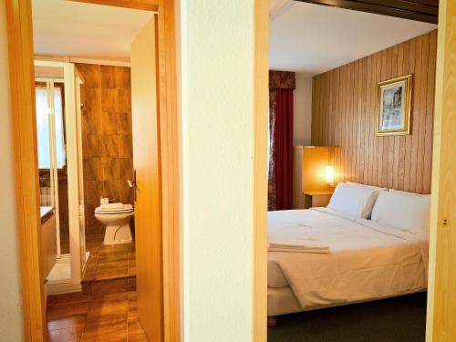 a bedroom with a bed and a bathroom with a toilet at Residence Les Coupoles in Champoluc