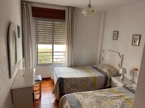a hotel room with two beds and a window at Piso Torrox Costa Málaga in Torrox