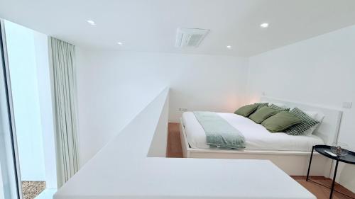 a white bedroom with a bed and a window at White Garden in Aveiro