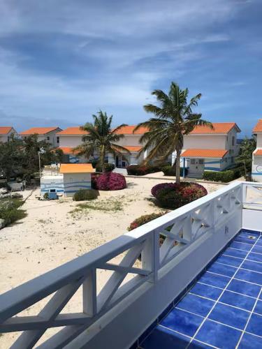 a balcony with a white fence and palm trees and buildings at Little Slice of Paradise in Westpunt
