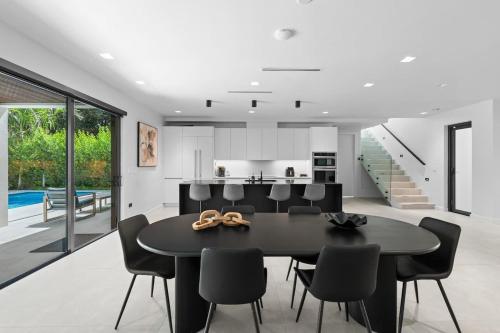 a dining room and kitchen with a black table and chairs at Absolut Luxe 5 Bed Villa with Pool- Great for Group in North Miami Beach