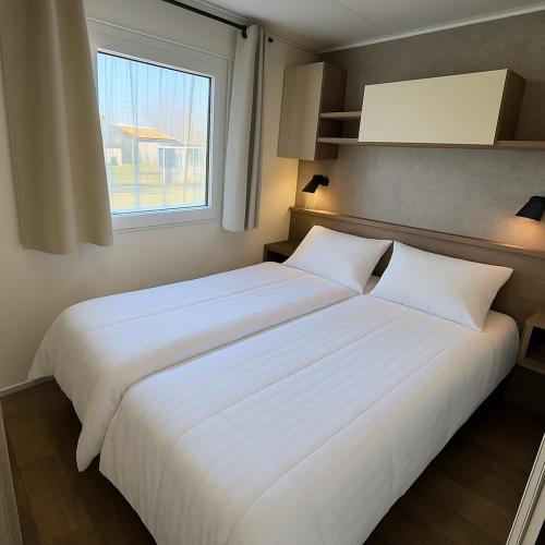 a large white bed in a room with a window at Chalet Flufstaart in Gasselte