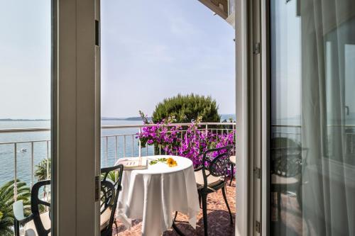a table on a balcony with a view of the water at Hotel Villa Florida & Suite Apartments in Gardone Riviera