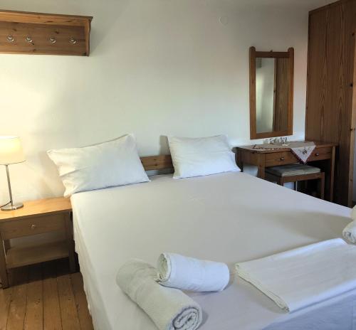 a bedroom with a large white bed and a mirror at Pension Niki in Skála Sykaminéas