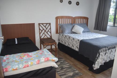 a bedroom with two beds and a chair at Casa Bela, perfeita para Descanso! in Morretes