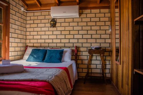 um quarto com uma cama em uma parede de tijolos em Morada Quatro Elementos - 150 Metros do Centrinho em Praia do Rosa