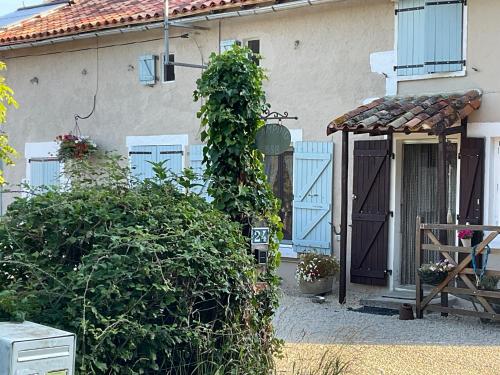 a house with a blue door and a bush at Le Jardin de Rose 24 FEUILLEBERT Romagne 86700 in Romagne