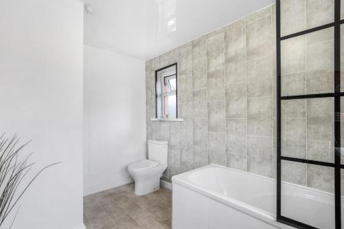 Un baño con bañera blanca y un inodoro. en 3Bedroom House - Free Parking, en Castleside