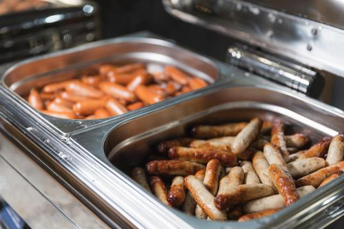 um recipiente com salsichas e cenouras no forno em Panorama by Verdi Hotels em Praga