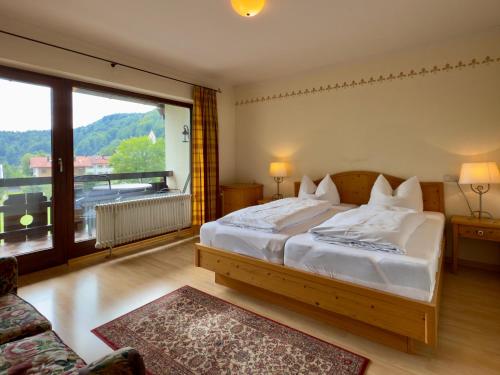 a bedroom with a large bed and a large window at Hotel Forsthaus Oberau in Oberau
