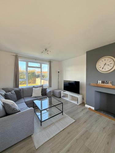 a living room with a couch and a clock on the wall at Grey haven - Central & 5 min from Southmead Hospital in Bristol