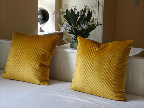two yellow pillows sitting on top of a bed at Donabate Entire Apt- 10min Airport in Donabate
