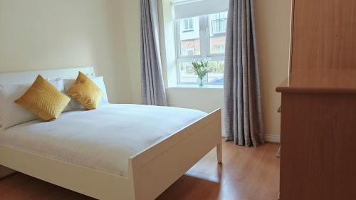 a bed with yellow pillows in a room with a window at Donabate Entire Apt- 10min Airport in Donabate