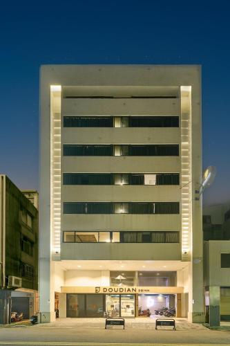 a large white building with benches in front of it at Doudian DDiNN Hotel in Taichung