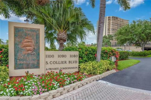 a sign in a park with flowers and palm trees at Rare desirable unit located in Shipps Landing III in Marco Island