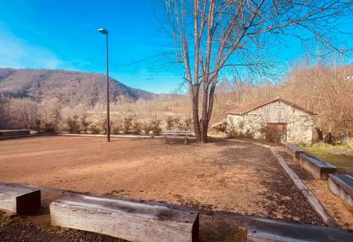 a park with a bench and a tree and a building at Le Refuge du Cagire in Aspet