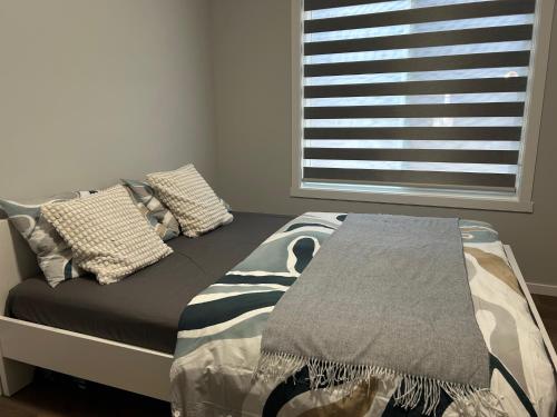 a bed with two pillows and a window in a room at 1-bedroom private suite, 20 minutes from the airport, with a kitchen in Edmonton