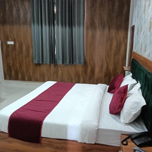 a bedroom with a white bed with red and white pillows at Hotel HAV Jaipur in Jaipur