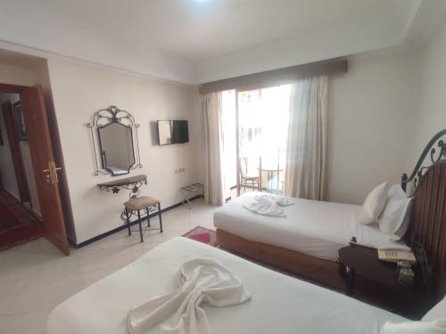 a hotel room with two beds and a mirror at Perla Hôtel in Fès