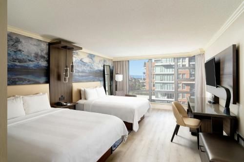 a hotel room with two beds and a desk and a television at Victoria Marriott Inner Harbour in Victoria