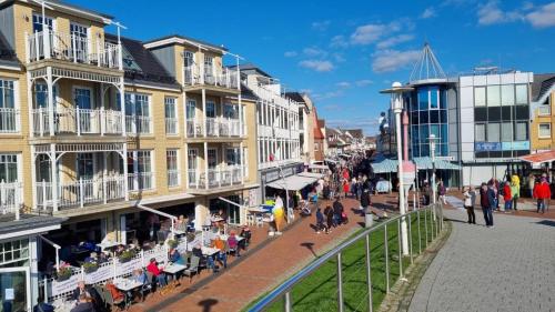 a street in a town with people sitting in chairs at Ferienwohnung Muschelbank No 4 in Büsum