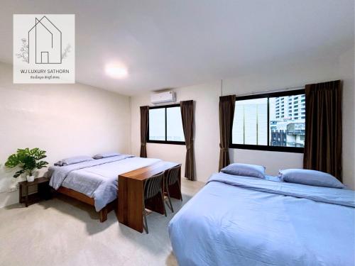 a bedroom with two beds and two windows at WJ Luxury Sathorn in Bangkok