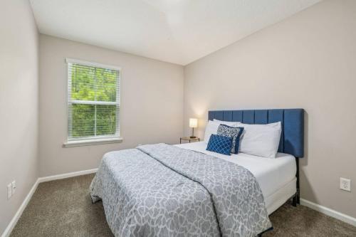 una camera da letto con un letto con testiera blu e una finestra di Isabella Ct Townhome a Orange Park