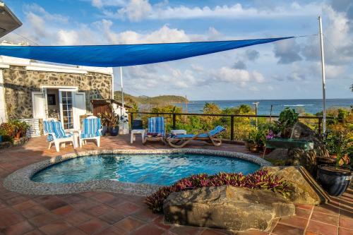 a swimming pool with chairs and a blue umbrella at Flip-Flops at Sapphire House in Laborie