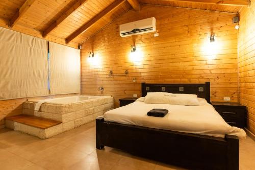 a bedroom with a bed and a bath tub at אצולת הכפר in Elifelet